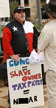 Dale Robertson, the leader of TeaParty.org, displays a handmade sign with a racial slur. Mediaite, the source of this photo, later blocked out a portion of the offending word. Robertson’s sign itself is not blocked out. 