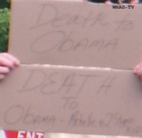 A protester displays a handmade sign advocating “Death to Obama” and to his family.