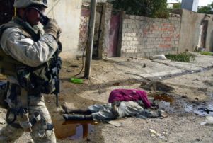 A Marine walks past several corpses strewn in a Fallujah street.