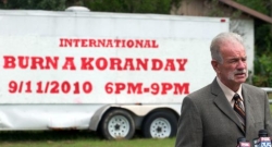 A photo of Terry Jones standing in front of a sign announcing ‘International Burn a Koran Day,’ originally planned for September 11, 2010.