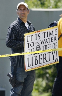 Protester William Kostric, bearing his sign and wearing a gun strapped to his leg.