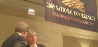 English-only advocates Pat Buchanan and white nationalist Peter Brimelow standing under misspelled banner.