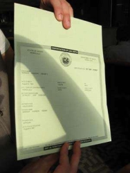 A photograph of the actual Hawaiian birth certificate of Barack Obama, being held by FactCheck (.org) writer Joe Miller.