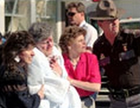 A bloodied survivor is helped from the Murrah bomb site.