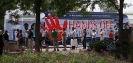 Patients First bus featuring the “Hands Off Our Health Care” slogan and bloody handprint logo.