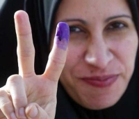 An Iraqi voter displays her purple finger for a reporter’s camera.