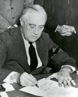 President Roosevelt signs the US declaration of war with Japan.