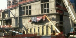 A crane begins removing an American flag from the ‘Ground Zero’ site of the former World Trade Center.