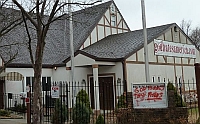 Part of the Westboro Baptist Church as it appears in recent years. The URL “godhatesamerica.com” is written on a banner hanging in front of the church.